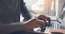 Business man hand typing on laptop computer keyboard with mobile smartphone on office desk at home, working from home, internet of things  concept