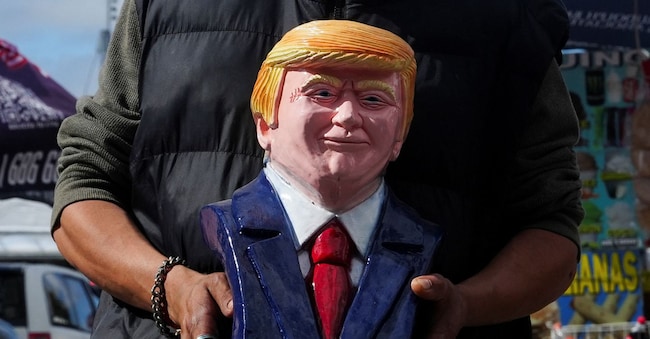 A vendor holds a bust of U.S. President Donald Trump at the San Ysidro border crossing in Tijuana, Mexico, March 12, 2025. REUTERS/Aimee Melo
