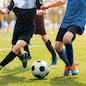 Two soccer players running and kicking a soccer ball. Legs of two young football players on a match. European football youth player legs in action