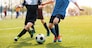 Two soccer players running and kicking a soccer ball. Legs of two young football players on a match. European football youth player legs in action