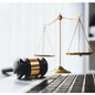 Symbolizing justice and legal authority, golden balanced scale and gavel on desk with laptop in law office background, reflecting concept of equality and fair judgment by lawyer and judge. equility