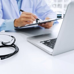 doctor working on laptop with  stethoscope and paper clipboard, selective focus