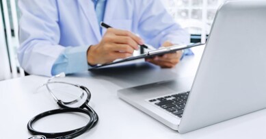 doctor working on laptop with stethoscope and paper clipboard, selective focus