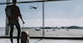 Guy is standing with luggage near window in waiting room. He is glancing at plane taking off outside. Copy space in right side