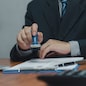 Man stamping approval of work finance banking or investment marketing documents on desk.