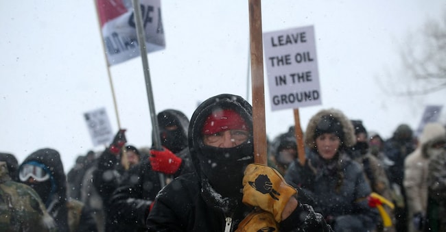 Un nativo americano guida una marcia di protesta con veterani e attivisti fuori dall’accampamento di Oceti Sakowin, dove i “protettori dell’acqua” continuano a manifestare contro i piani di far passare l’oleodotto Dakota Access adiacente alla riserva indiana di Standing Rock, vicino a Cannon Ball, Dakota del Nord, Stati Uniti, 5 dicembre 2016. (Reuters/Stephen Yang)
