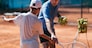 Tennis instructor with young boy in tennis training lesson