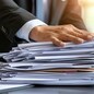 A businessman with a bundle of paper documents in hand.