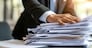 A businessman with a bundle of paper documents in hand.
