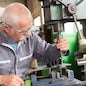 elderly worker watches processing of detail on milling machine