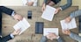 Business people discuss contract sitting around office table, top view
