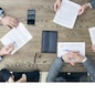 Business people discuss contract sitting around office table, top view
