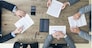 Business people discuss contract sitting around office table, top view
