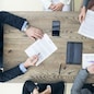 Business people discuss contract sitting around office table, top view