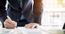 Businessman writing in a document. Focus on the tip of the pen.