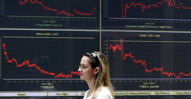 Una donna cammina davanti ai tabelloni elettronici che mostrano i prezzi delle azioni e l’indice economico alla borsa di Atene.(  REUTERS/John Kolesidis)