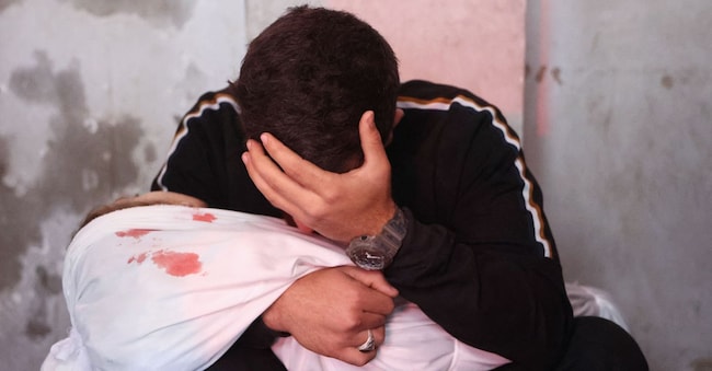 Un uomo palestinese piange mentre tiene in braccio il corpo avvolto in un sudario di un parente, ucciso in un presunto attacco israeliano, prima del loro funerale all’ospedale Ahli Arab, a Gaza City il 6 aprile 2025. (Omar al-Qattaa/Afp)