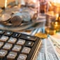 Calculator with currency glass jar and gold coins stack, dollar and euro banknotes on the table. Compound interest rate calculation or financial investment business concepts