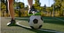 Closeup male foot in boots on soccer ball over green grass field background. Outdoor sport activity for adults