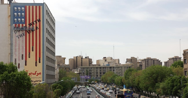 Iraniani guidano accanto a un murale anti-USA in una strada, a Teheran, Iran, 8 aprile 2025. Il ministro degli Esteri iraniano Abbas Araqchi ha dichiarato l’8 aprile che alti funzionari iraniani e statunitensi terranno negoziati indiretti in Oman il 12 aprile. EPA/ABEDIN TAHERKENAREH