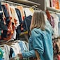Woman in medical mask choosing clothes in outlet store.