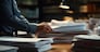 Businessman hands working in Stacks of paper files for searching information on work desk in office, business report papers,piles of unfinished documents achieves.Created with Generative AI technology.
