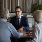 Male Caucasian specialist have meeting with mature couple clients, discuss health insurance for older people. Middle-aged spouses customers consult with relator or broker. Realty, rent concept.