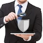 people, internet security and cyber protection concept - businessman holding magnifying glass over tablet pc computer with virtual antivirus program shield icon