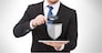 people, internet security and cyber protection concept - businessman holding magnifying glass over tablet pc computer with virtual antivirus program shield icon
