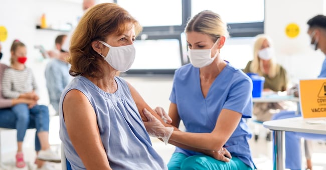 Old woman with face mask getting vaccinated, coronavirus, covid-19 and vaccination concept.