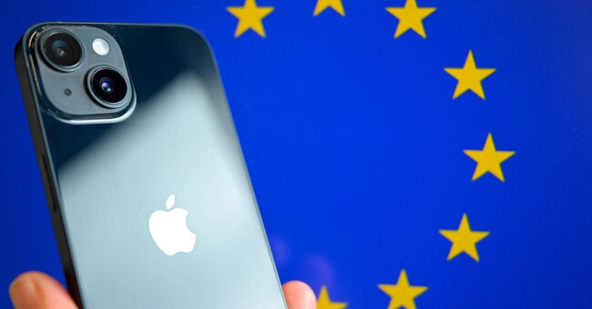 (FILES) This photograph shows a hand-held smartphone with the Apple company logo and the European Union logo in the background, in Brussels on September 9, 2024. The EU slapped Apple and Meta with 700 million euros in fines for breaking the bloc's digital competition rules, risking the wrath of US President Donald Trump, on April 23, 2025. (Photo by Nicolas TUCAT / AFP)