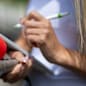 Female news reporter or TV journalist at press conference, holding microphone and writing notes