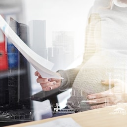 pregnancy, business and work concept - smiling pregnant businesswoman sitting at office table and reading papers over urban double exposure effect