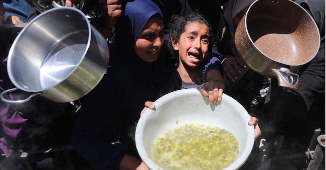 Una bambina piange tra  i palestinesi che aspettano di ricevere cibo cucinato da una cucina di beneficenza, a Beit Lahia, nel nord della striscia di Gaza, 8 maggio 2025 (Reuters/Mahmoud Issa)