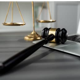 Symbolizing justice and legal authority, golden balanced scale and gavel on desk with laptop in law office background, reflecting concept of equality and fair judgment by lawyer and judge. equility