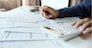 Close-up shot. business owner holding pencil checking report documents and use calculator to manage financial documents bills invoices pay utilities calculate business commercial cost income and tax