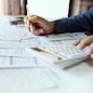 Close-up shot. business owner holding pencil checking report documents and use calculator to manage financial documents bills invoices pay utilities calculate business commercial cost income and tax