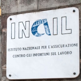 Carrara, Italy - May 28, 2020 - Marble plaque at the entrance of an Inail building (Italian National Institute for Insurance against Accidents at Work)
