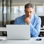 Busy serious middle aged professional business man financial investor, 50 year old senior businessman executive wearing suit using laptop computer working on investment project sitting at office desk.