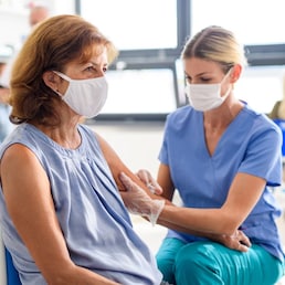 Old woman with face mask getting vaccinated, coronavirus, covid-19 and vaccination concept.