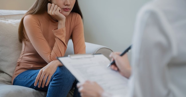 Young woman in a mental therapy session talking with a psychologist in the office. Pormezz - stock.adobe.com
