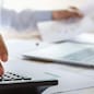 accountant working on desk using calculator for calculate finance report in office