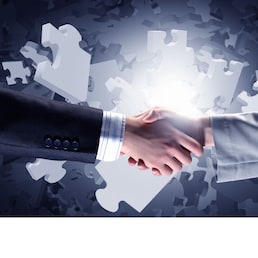 Close up of business handshake with puzzle elements at background