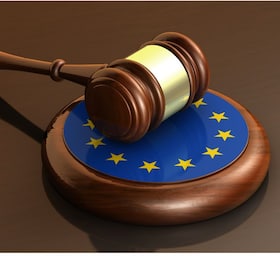 European Union laws, legal system and parliament concept with a 3d render of a gavel on a wooden desktop and the EU flag.