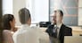 Smiling male realtor or broker shaking hand of excited buyers couple, negotiating about first house purchase or taking loan, insurance agent welcoming clients with handshake at consultation meeting