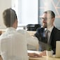 Smiling male realtor or broker shaking hand of excited buyers couple, negotiating about first house purchase or taking loan, insurance agent welcoming clients with handshake at consultation meeting