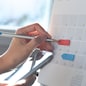 Event planner timetable agenda plan on organize schedule event. Business woman checking planner on mobile phone and taking note on calendar desk on office table. Calendar event plan, work planning, project management concept