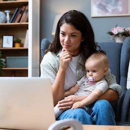 Young female business owner work on laptop from home during maternity leave, running private company with baby in her lap. Businesswoman mother woman with a toddler working at the computer.
