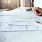 Close-up shot. business owner holding pencil checking report documents and use calculator to manage financial documents bills invoices pay utilities calculate business commercial cost income and tax