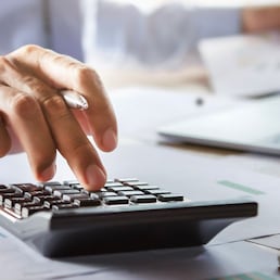 accountant working on desk using calculator for calculate finance report in office